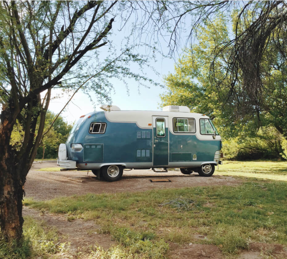 Old style, blue camper van sitting in the woods